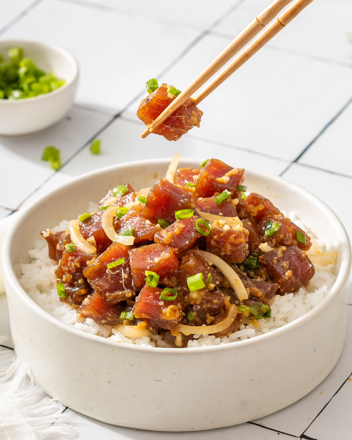 Someone lifting up a piece of tuna from a Hawaiian poke bowl.