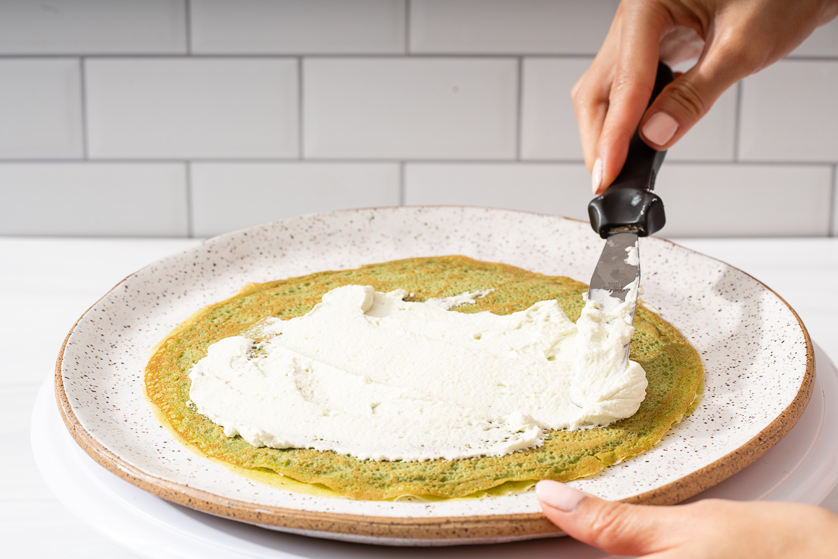 Spreading the matcha whipped cream onto a crepe.