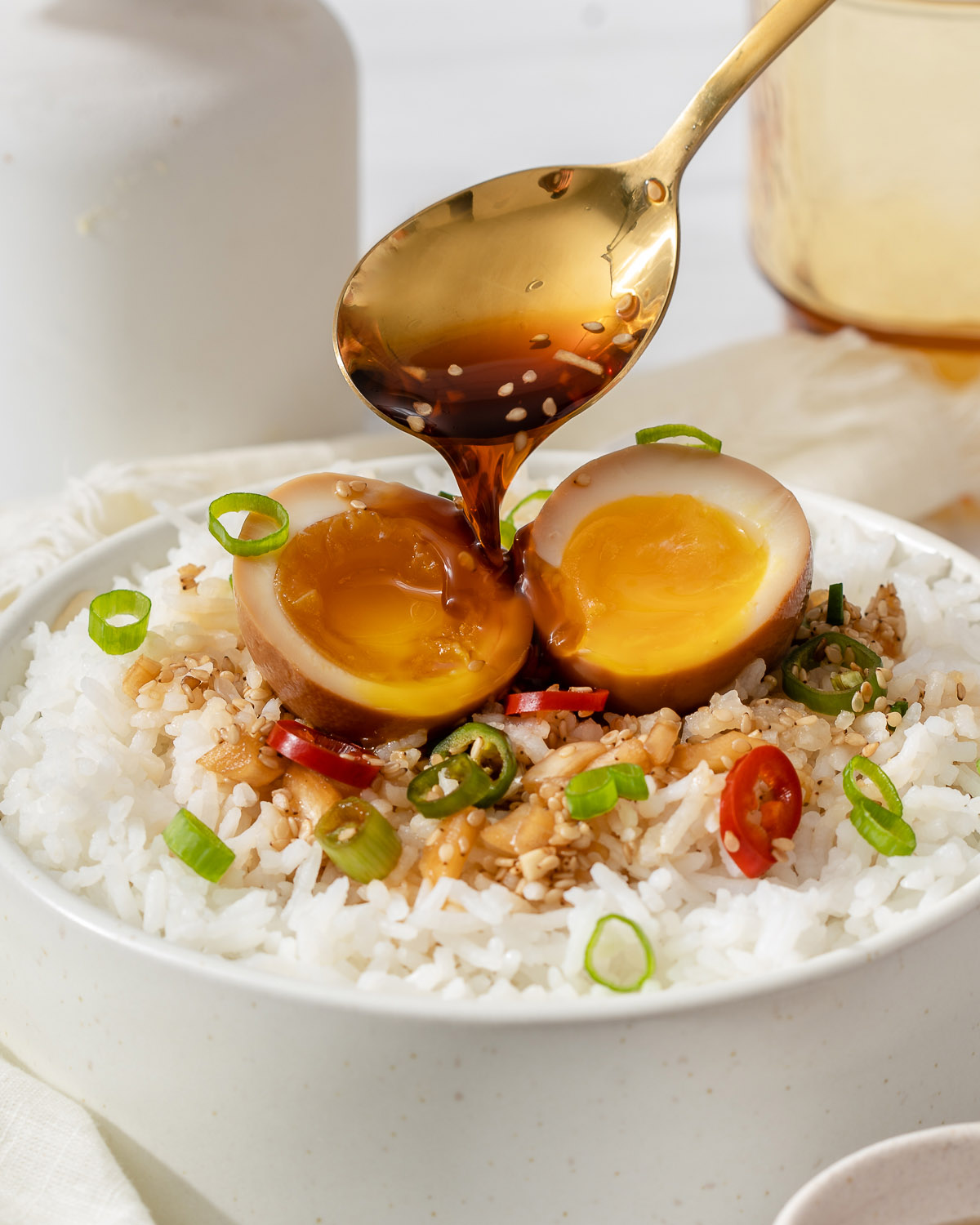 Pouring sauce onto a sliced open mayak egg on rice.