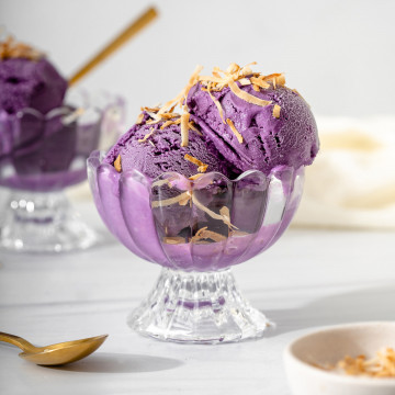 Up close of a small dish of ube ice cream topped with toasted coconut.