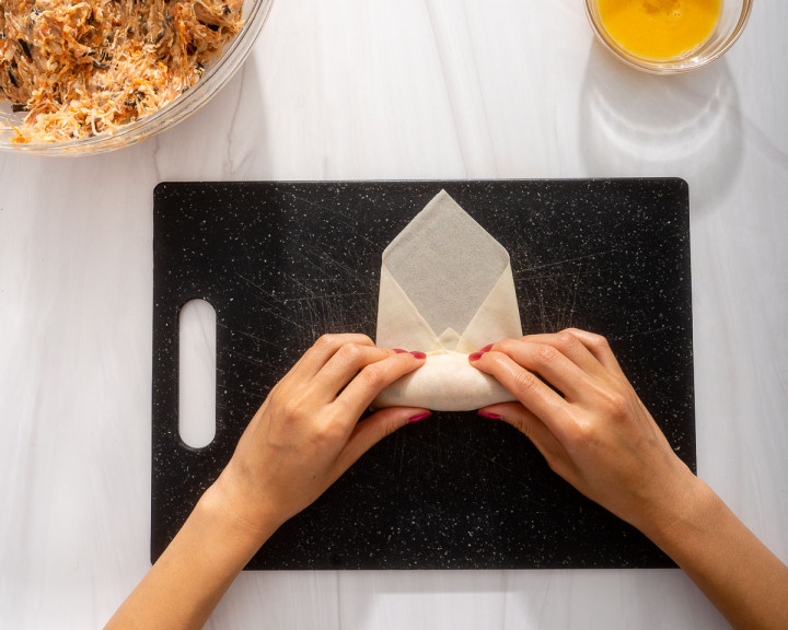 Rolling the egg roll wrapper tightly.