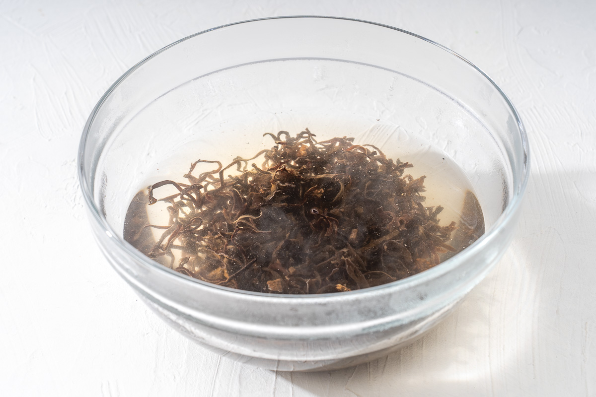 Shredded woodear mushrooms being soaked in water.