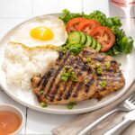 Up close of a plate of Vietnamese pork chops and traditional sides.