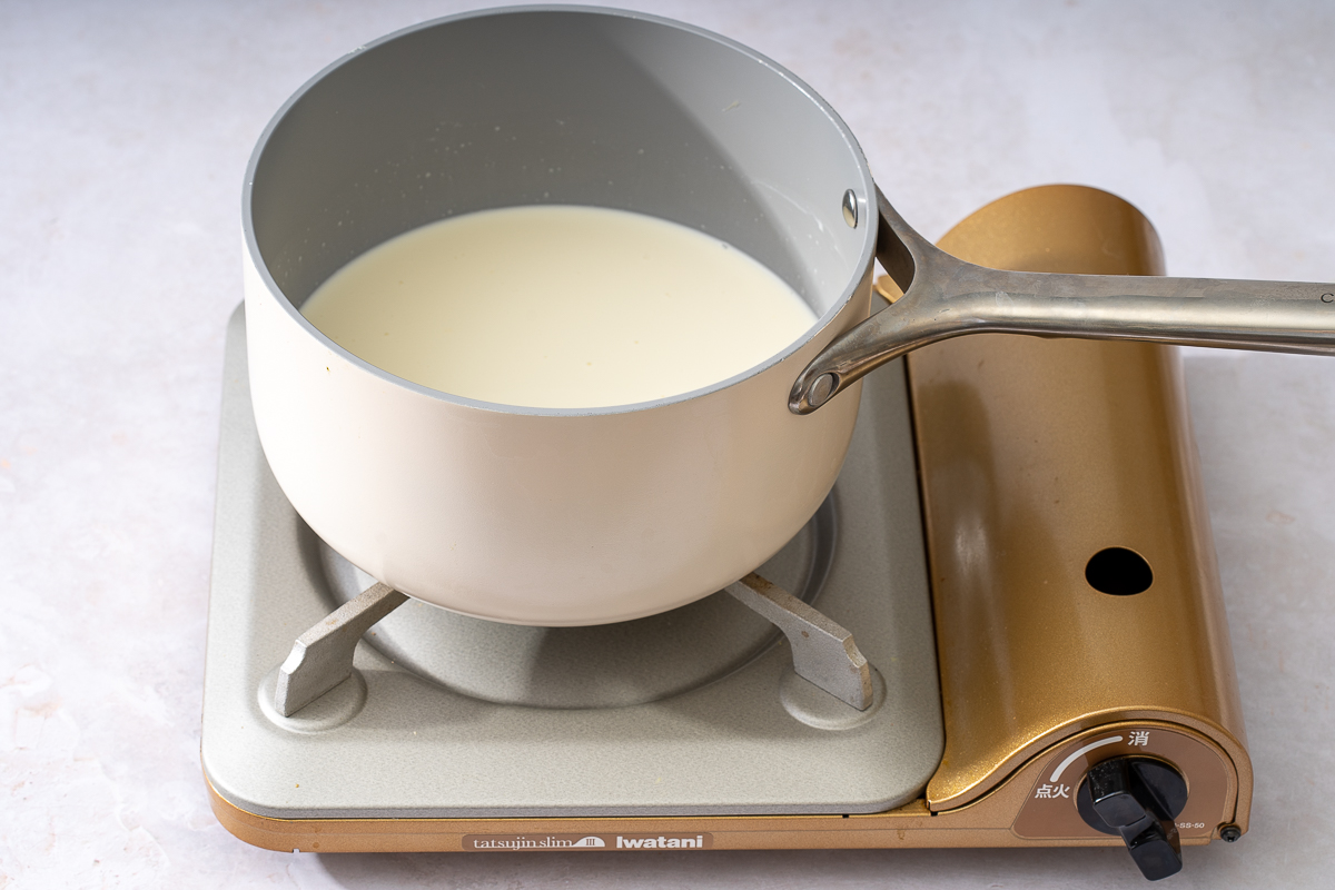 Heating heavy cream and coconut milk in a sauce pan.