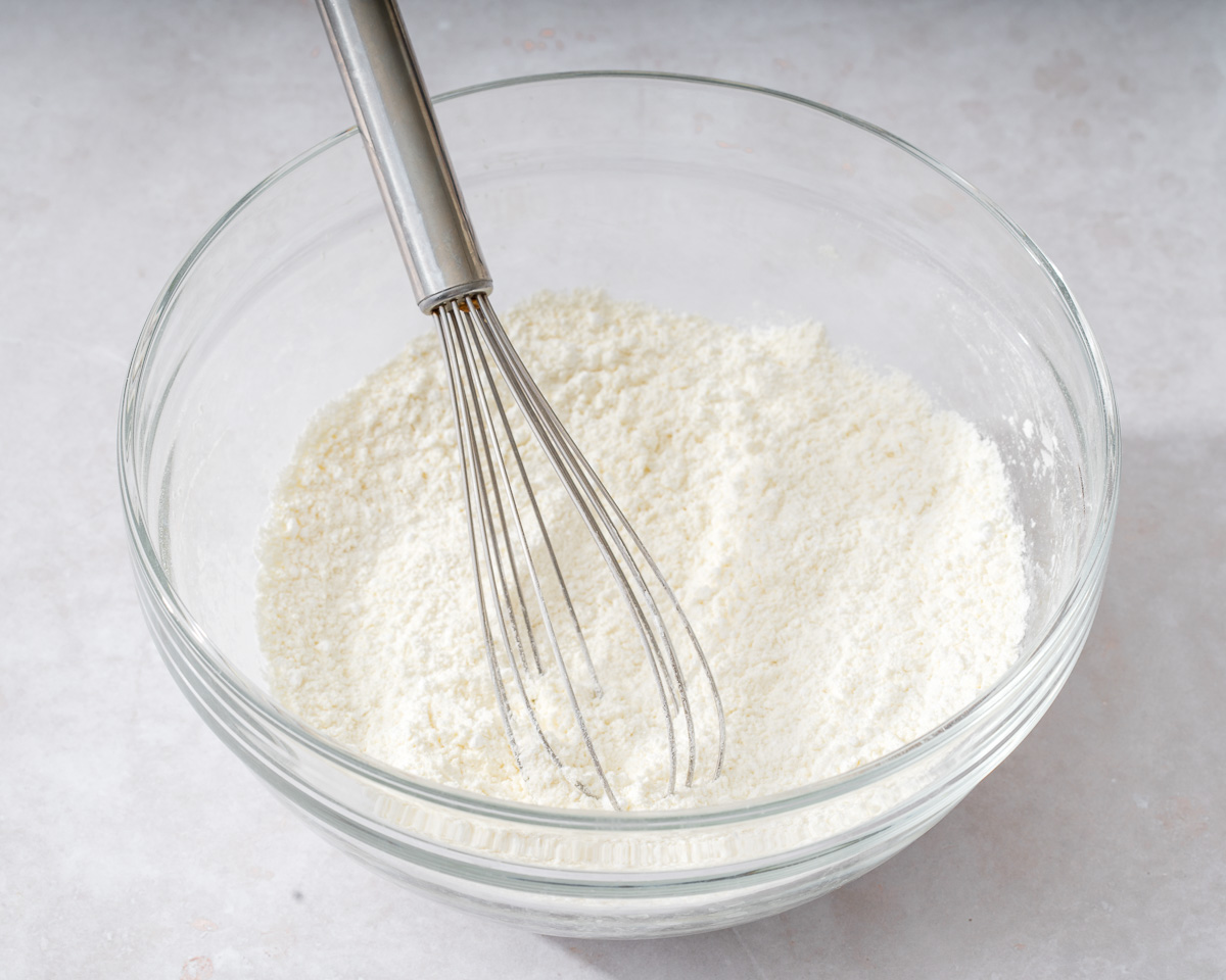 Sifting dry ingredients inside a mixing bowl.
