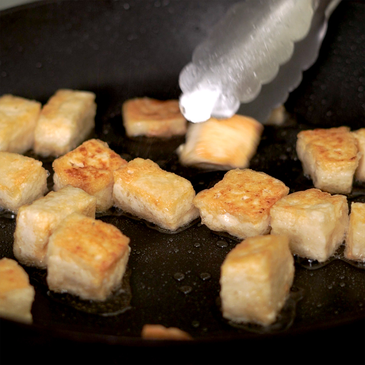 Pan frying tofu in a large skillet.