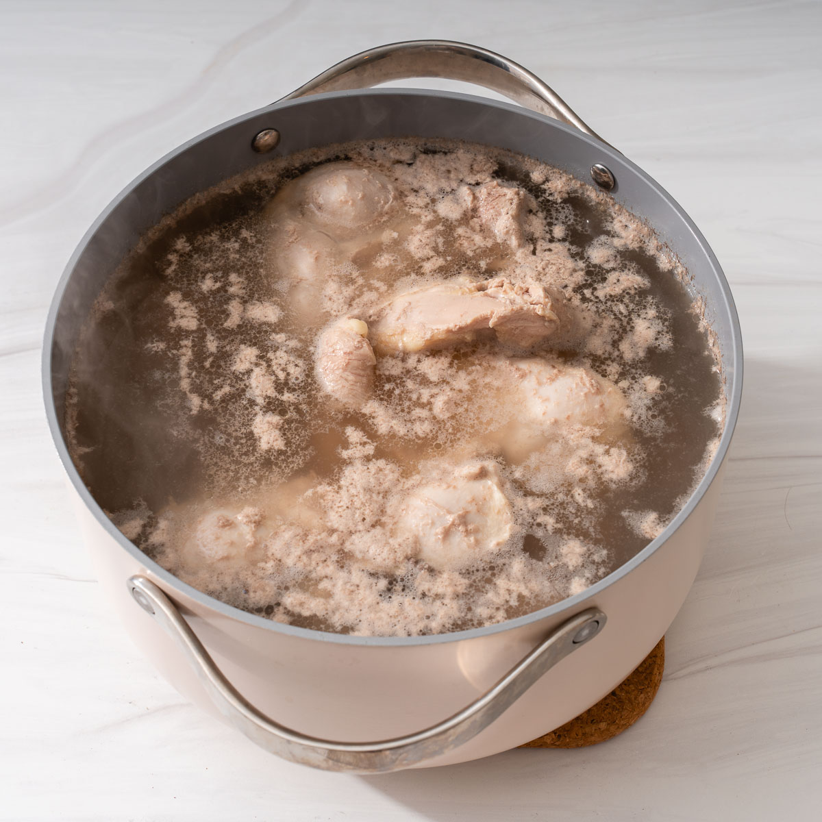 Blanching the pork and chicken in a large pot of water.