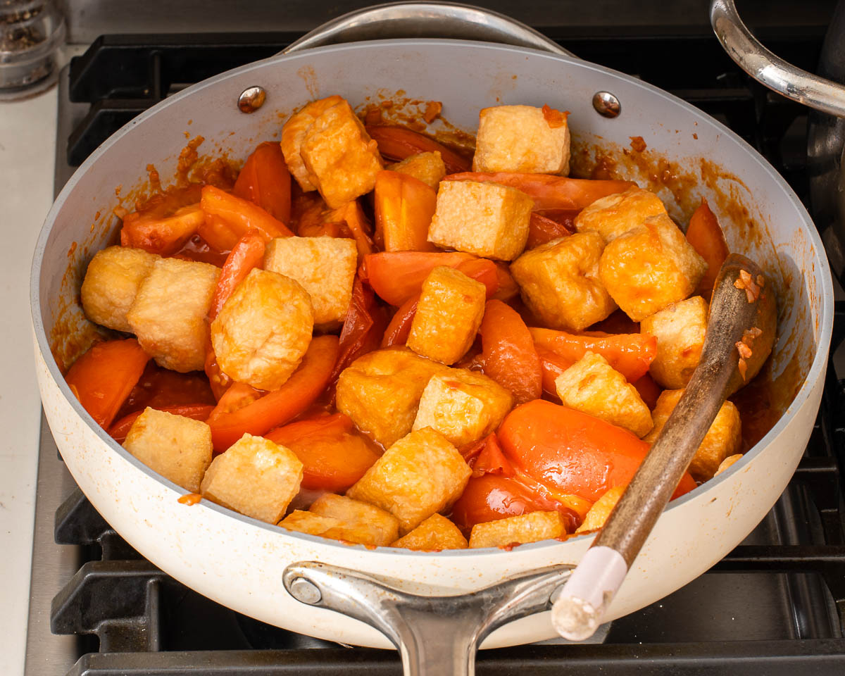 Sautering the tomatoes and tofu in a large skillet.