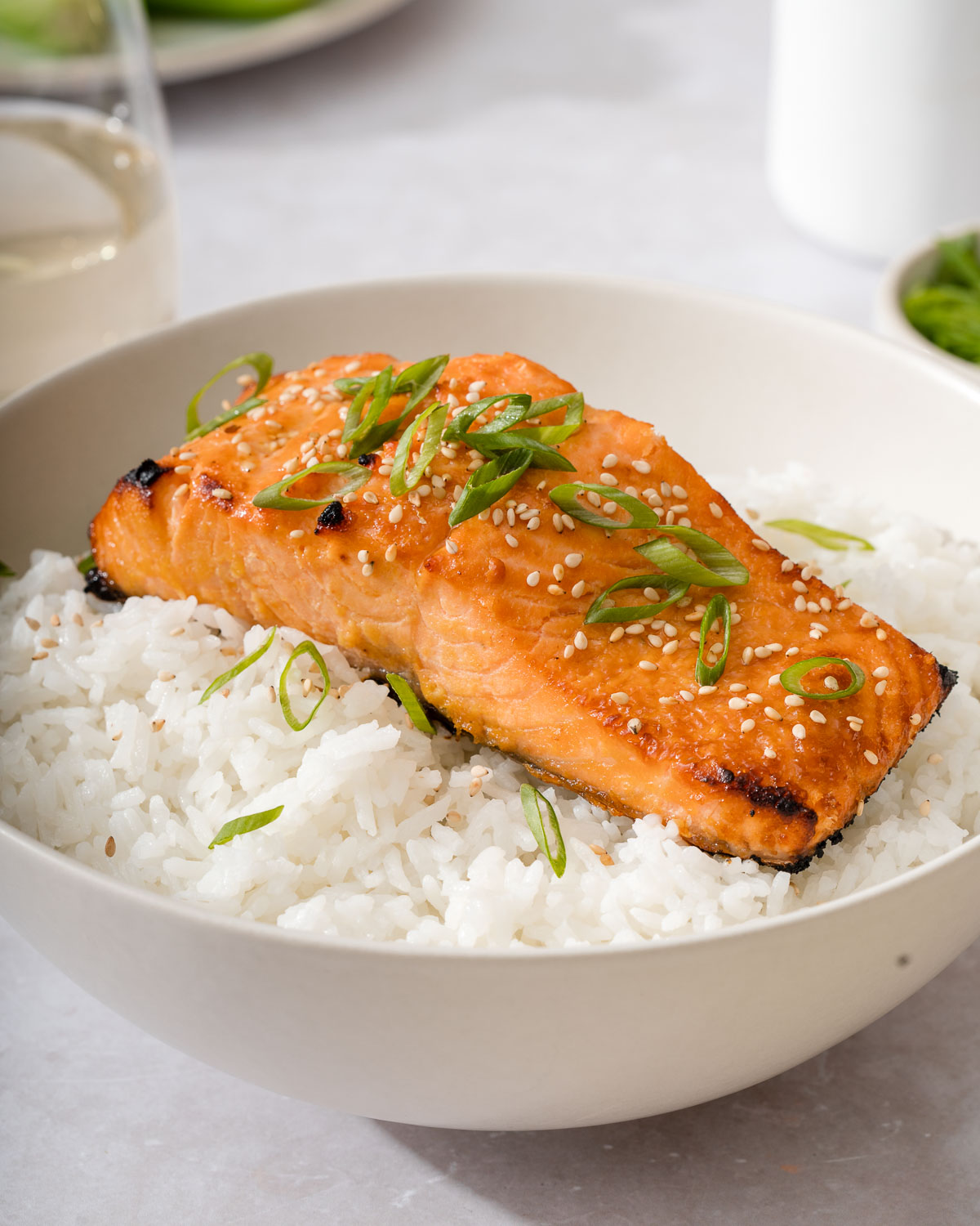 A bowl of rice topped with a plank of miso salmon.