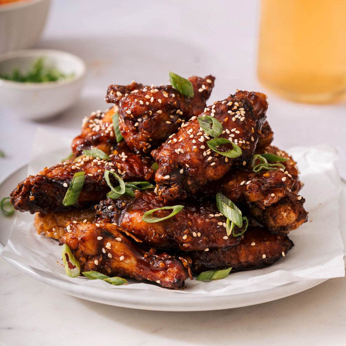Up close with a plate of soy garlic chicken wings garnished wit sesame seeds and green onion.