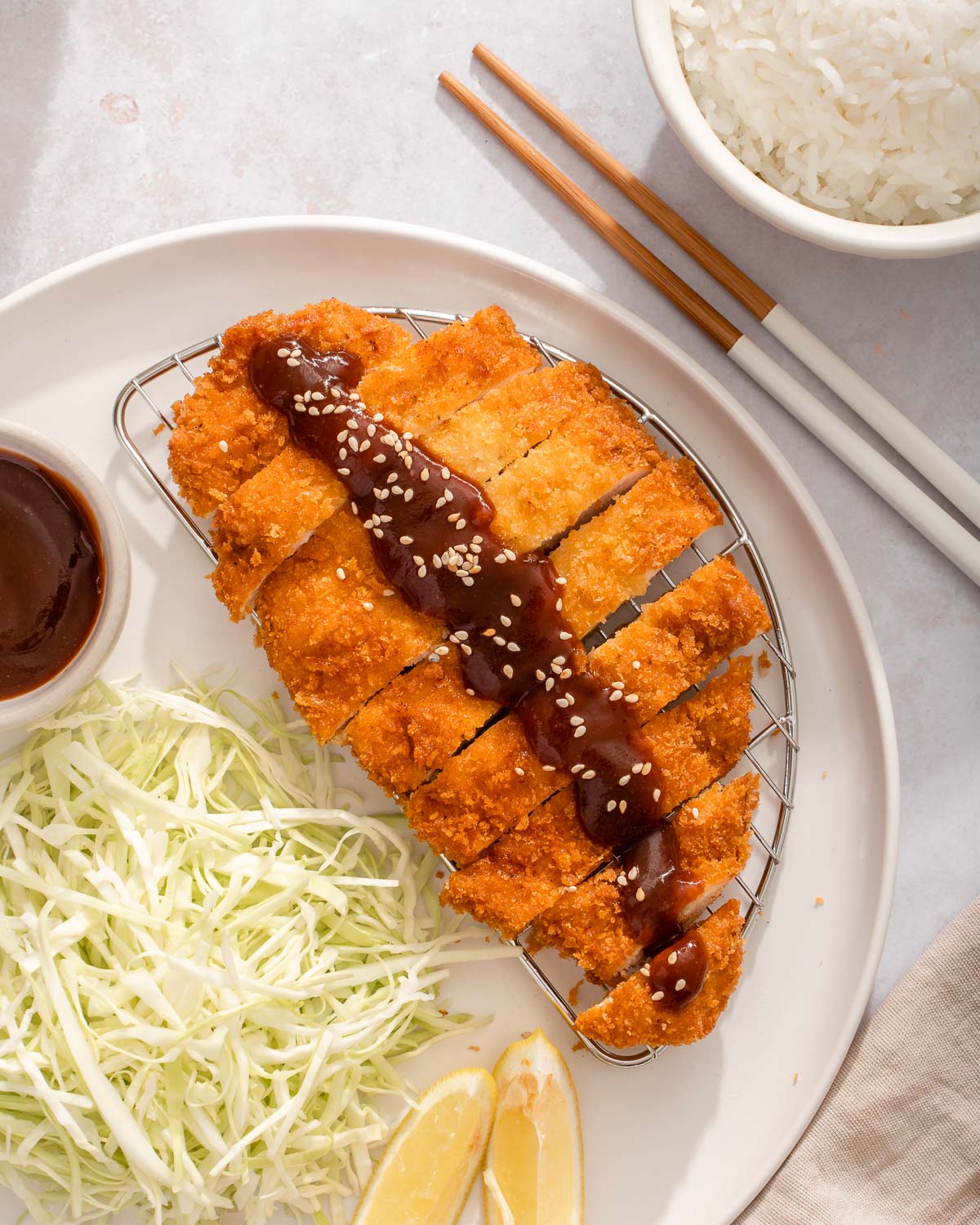 A chicken katsu topped with homemade katsu sauce and toasted sesame seeds.