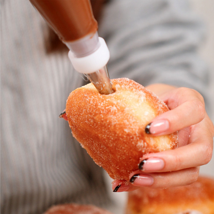 Piping nutella into the hole of a milk bread donut.