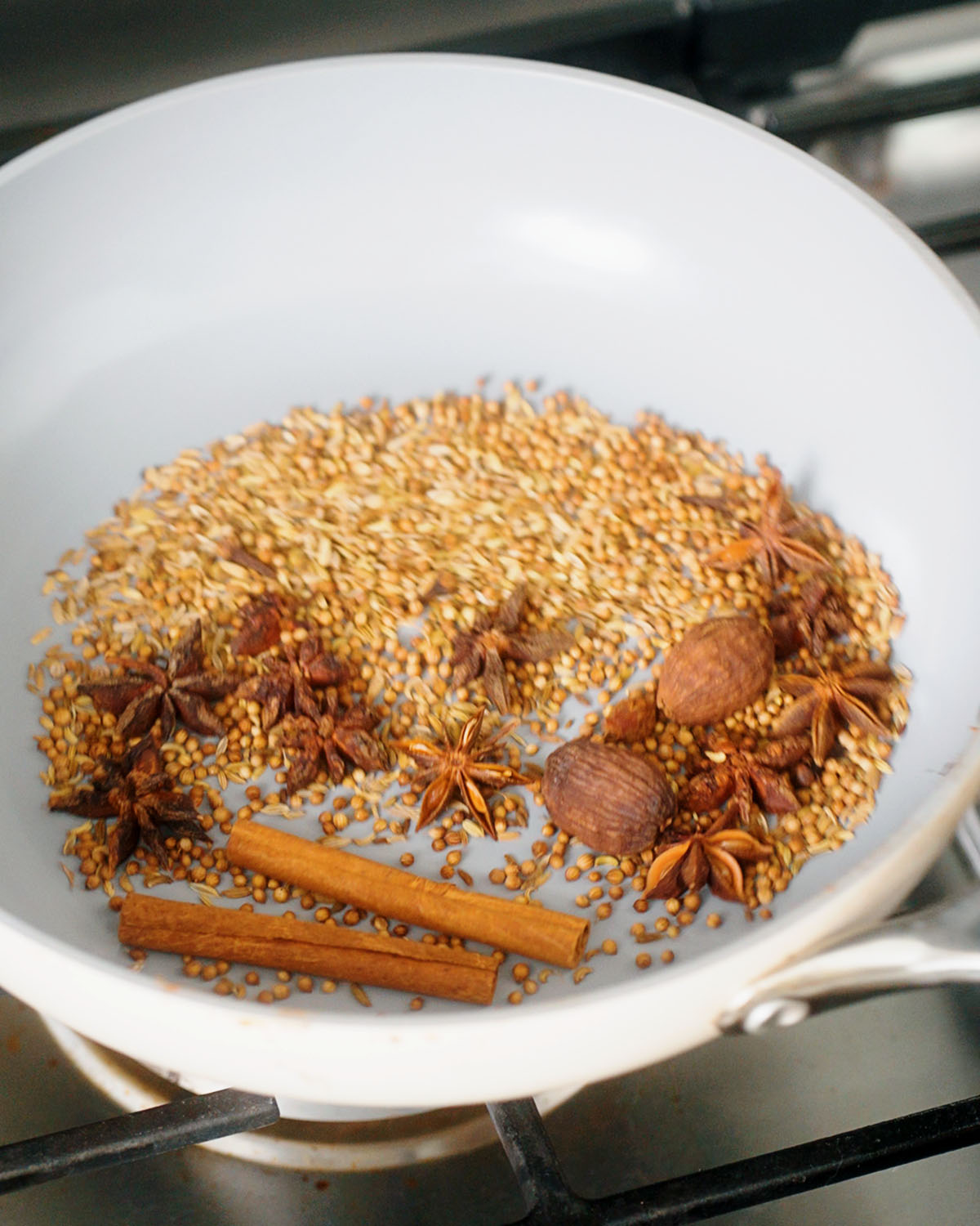 Toasting the spices for a pho spice bag in a large skillet on the stove.