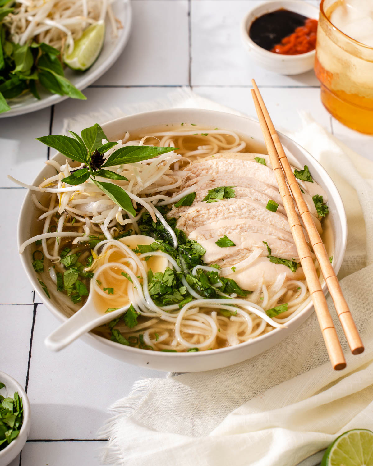 Up close with a bowl of pho ga surrounded by table settings.