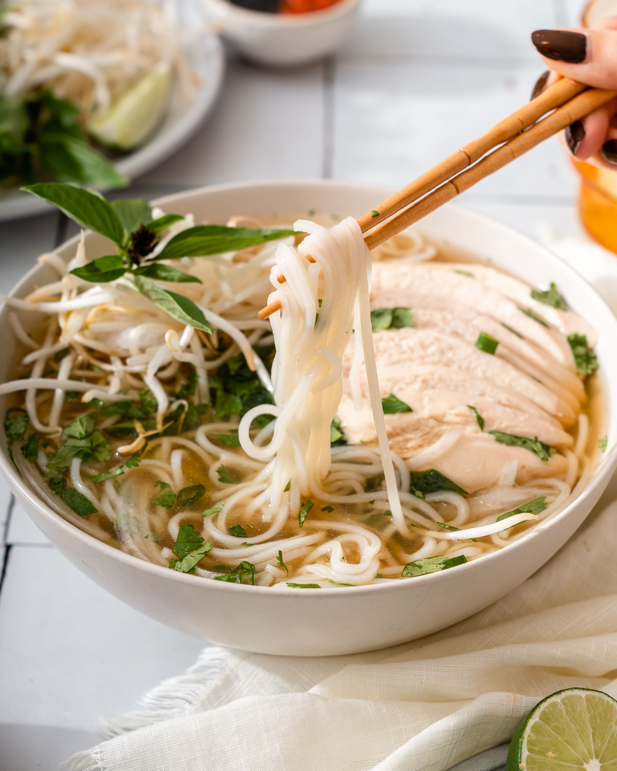 Someone lifting up noodles from a bowl of chicken pho.