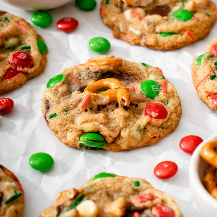 Up close with a christmas monster cookie sitting on parchment paper with m&m's.
