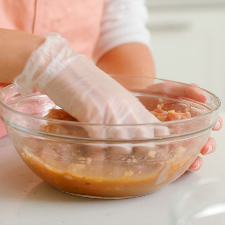 Mixing the sliced chicken into the marinade mixture.