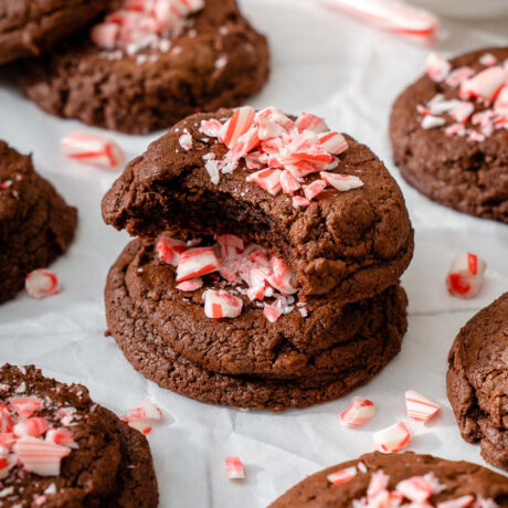 A stack of fudgy peppermint brownie cookies sitting on parchment paper.