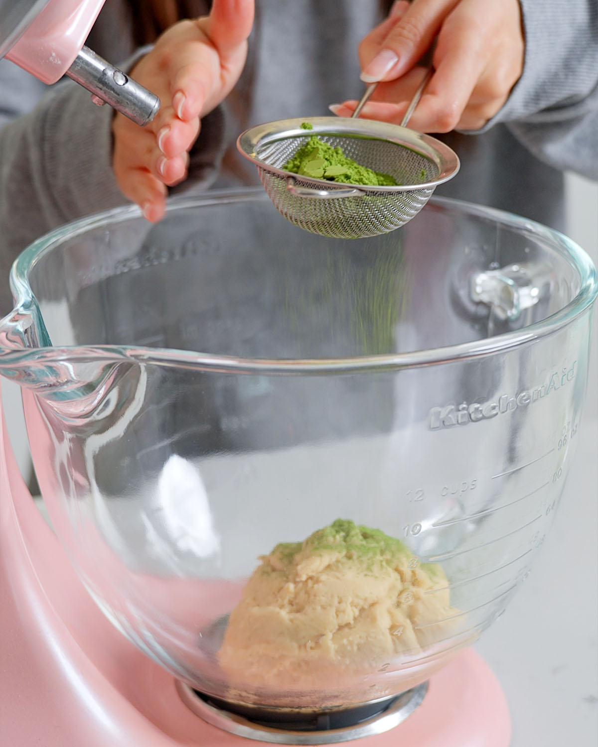Sifting the matcha into the bowl with the dough to mix.