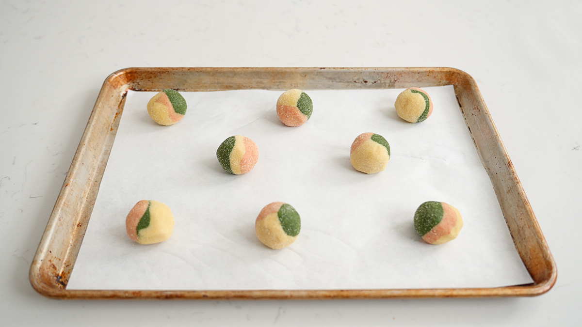 The assembled strawberry matcha neapolitan cookies spaced evenly on a parchment lined baking try.