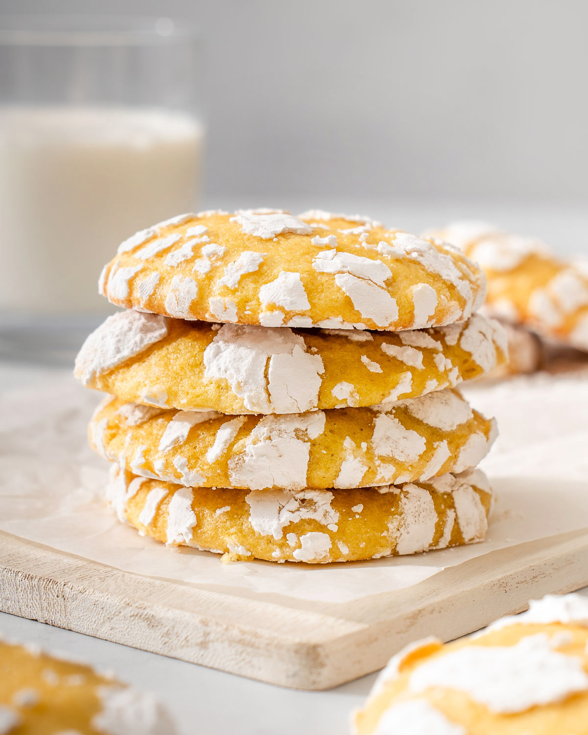 A stack of yuzu lemon crinkle cookies on parchment paper.