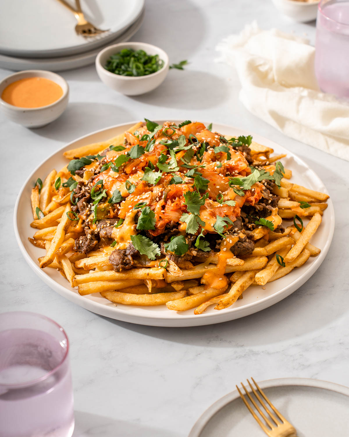 A plate of bulgogi fries in the middle of a table spread.