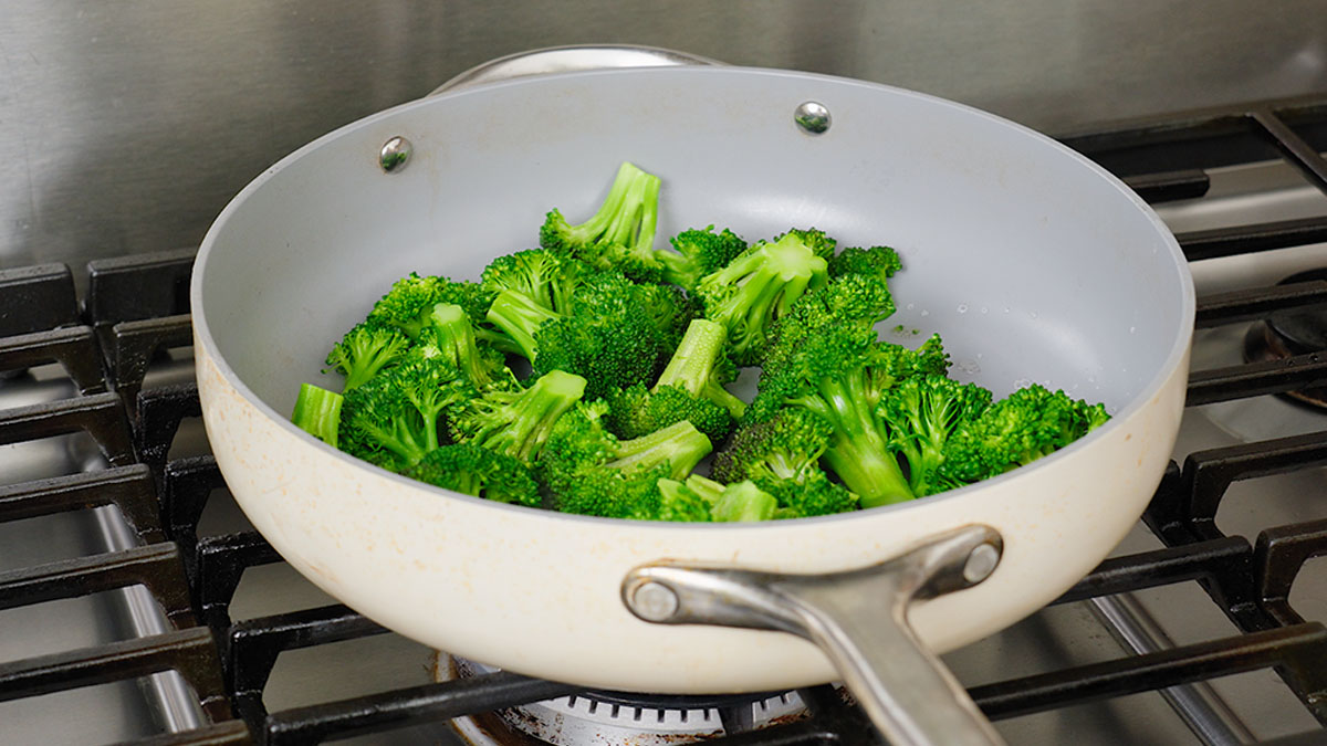 Steaming the broccoli in the large pan with a little bit of water.