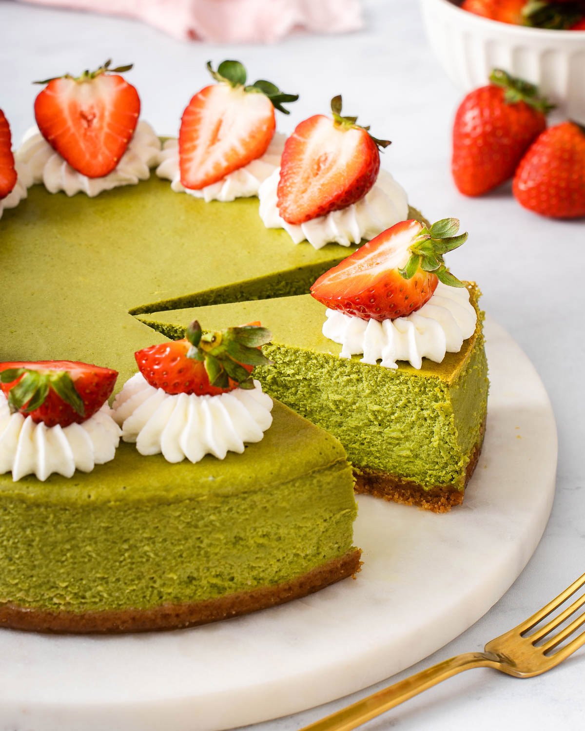 A sliced matcha cheesecake with strawberries.