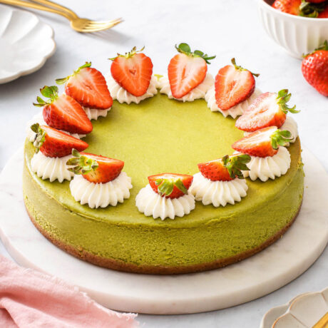 Up close with a matcha cheesecake topped with strawberries and whipped cream.