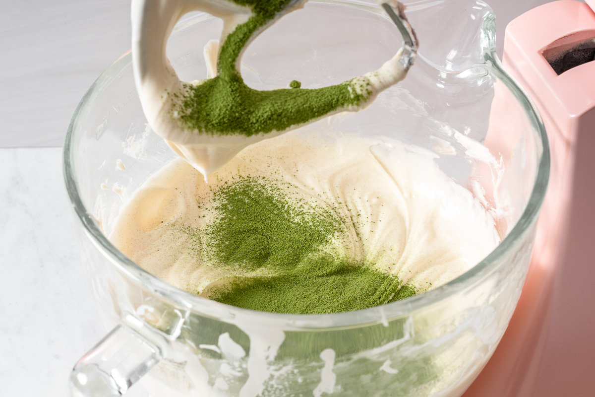 Matcha sifted into a mixing bowl with sweetened cream cheese.