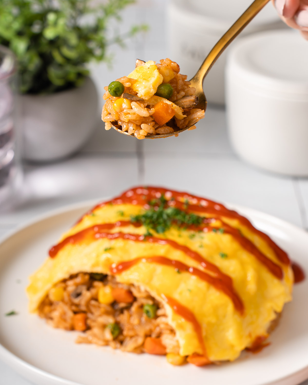 Someone lifting up a spoonful of fried rice from a plate of omurice.