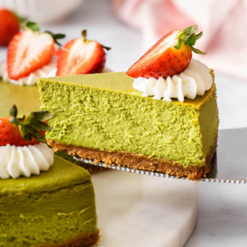 Liting up a slice of matcha cheesecake from the whole cheesecake.