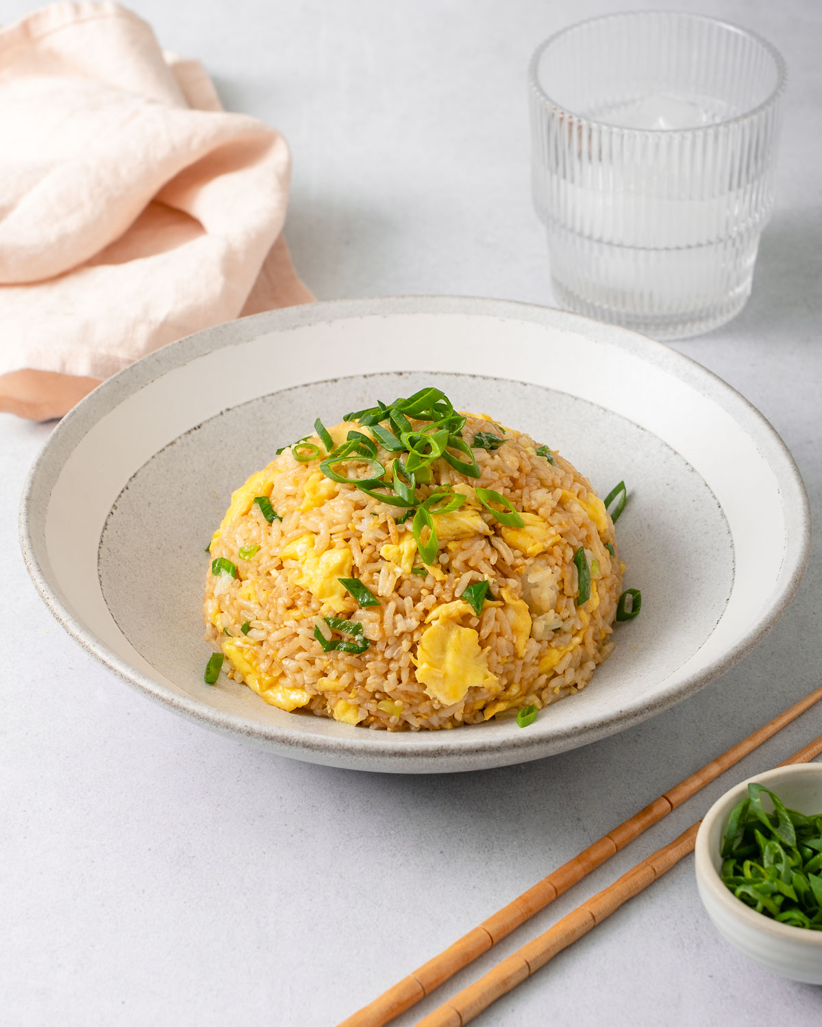 A bowl of egg fried rice topped with sliced green onion.