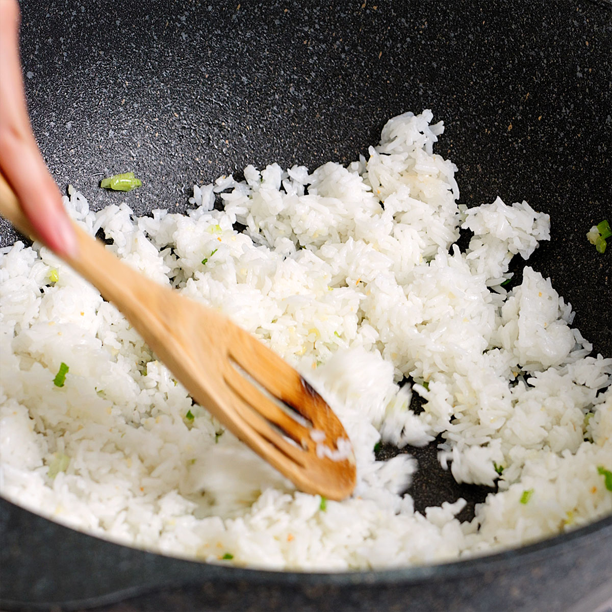 Mixing the rice with the sautéed aromatics in the wok.