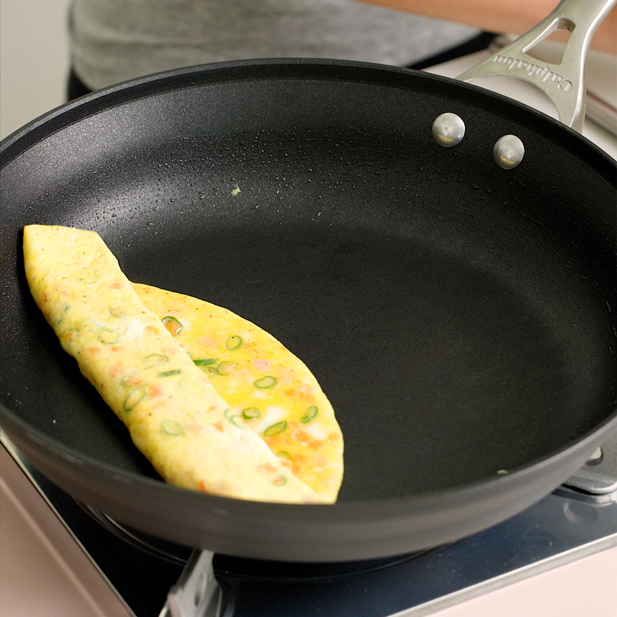 A Korean egg rolls lid to the side of the pan to add remaining egg mixture.