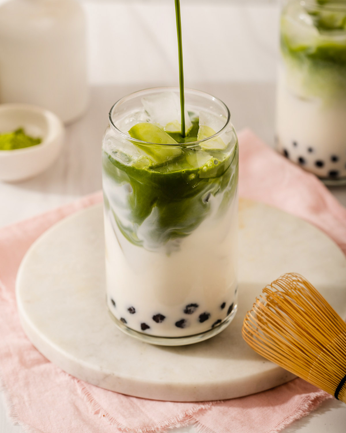 Pouring the matcha into a glass with milk and tapioca pearls.