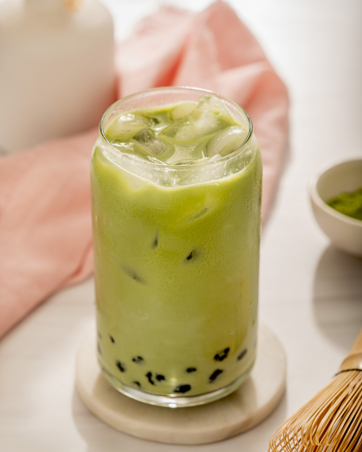 Up close with a glass of blended matcha milk tea with boba pearls.