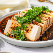 Up close with silken tofu on a plate garnished.