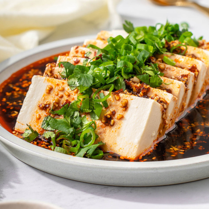 Up close with silken tofu on a plate garnished.