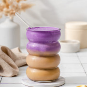 An iced ube latte sitting on a coaster.