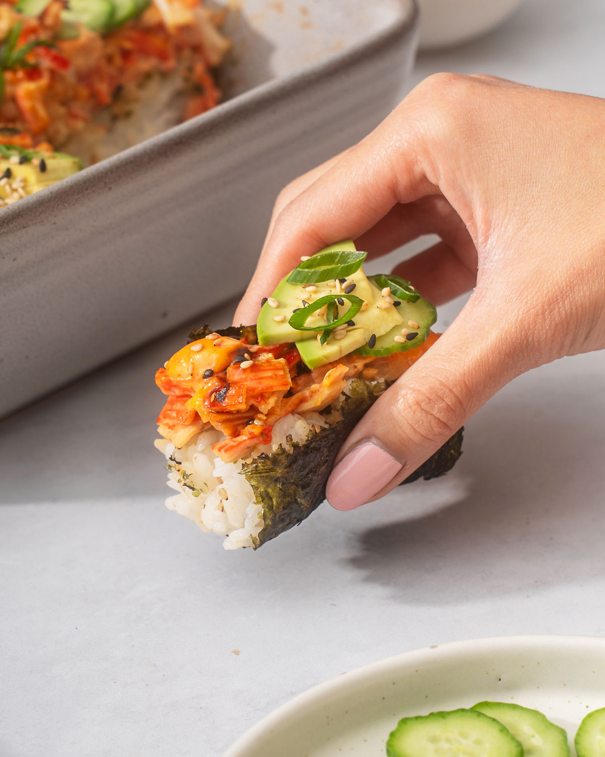 Holding a slice of sushi bake in a seaweed snack.