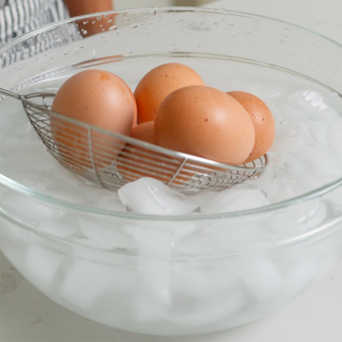 Placing freshly soft boiled eggs into an ice bath.