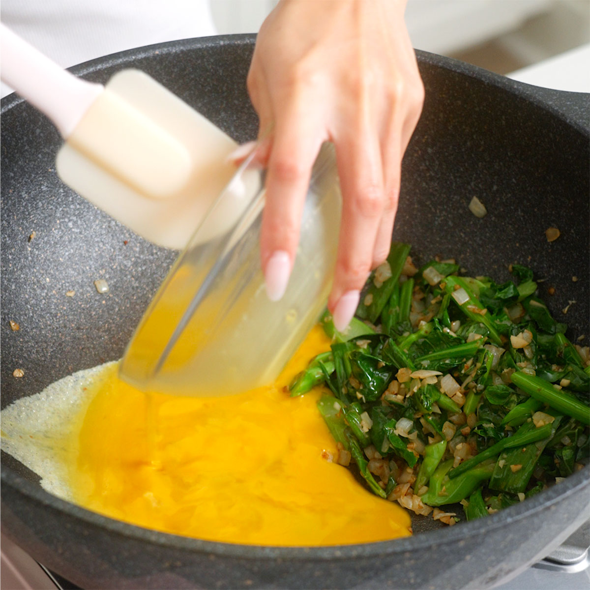 Pouring egg batter into a wok.