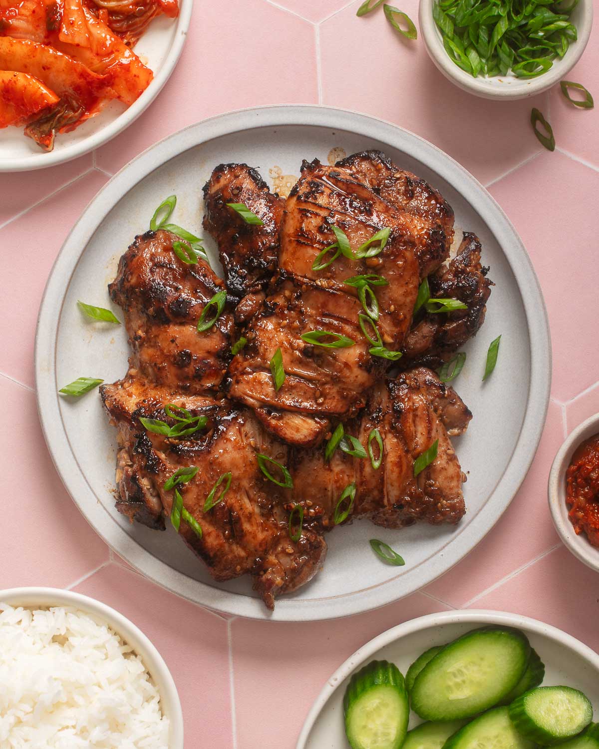 Looking down at a plate of Korean bulgogi chicken with sides around it.