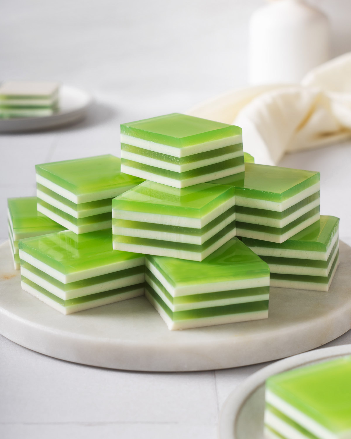 A round tray stacked with layered coconut pandan jelly.