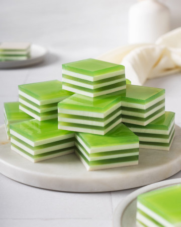 A round tray stacked with layered coconut pandan jelly.