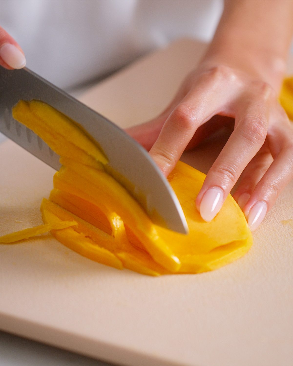 Thinly slicing mango cheeks into matchsticks.