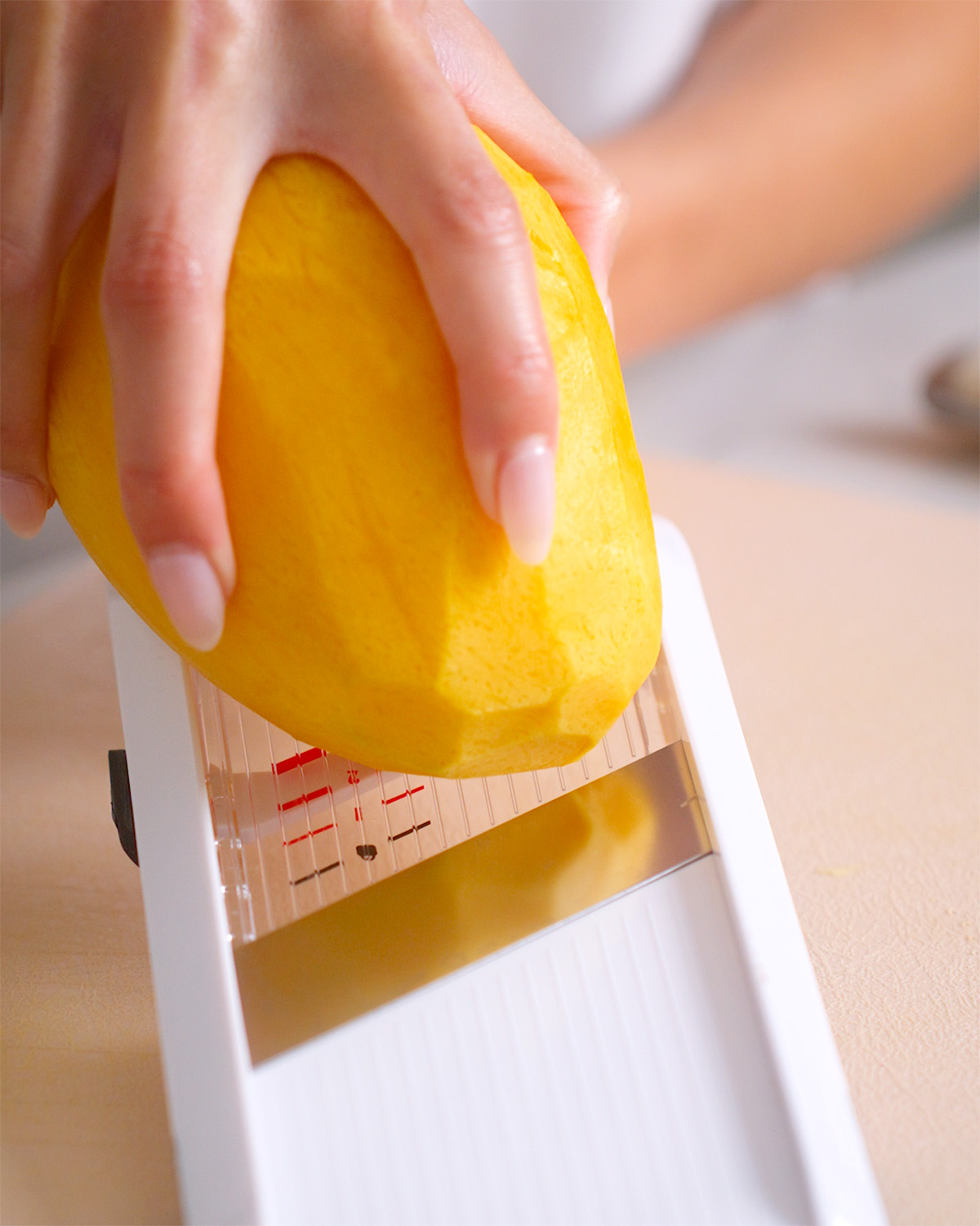 Slicing a mango with a mandoline for even slices.