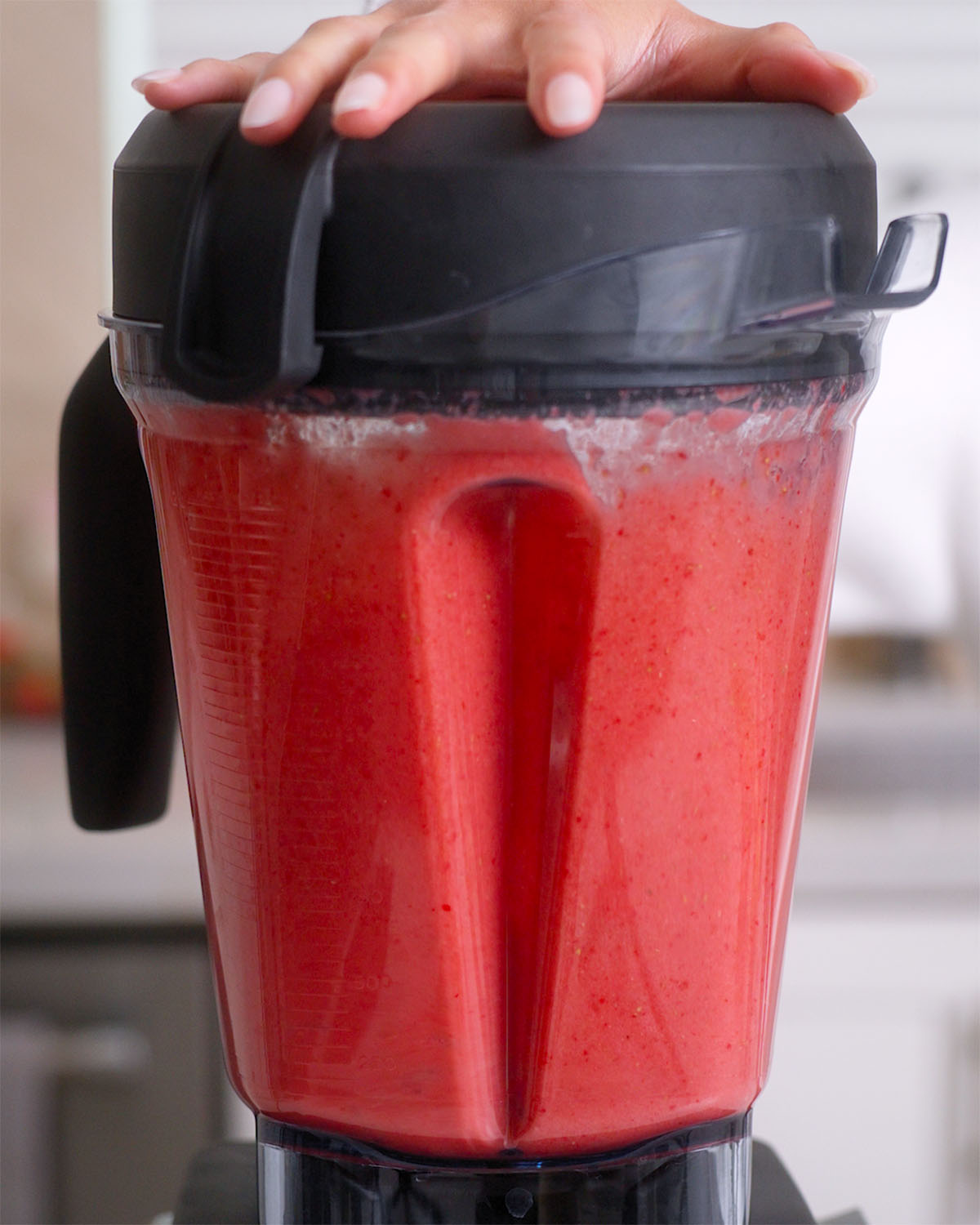 Blending strawberries inside a blender into a puree.