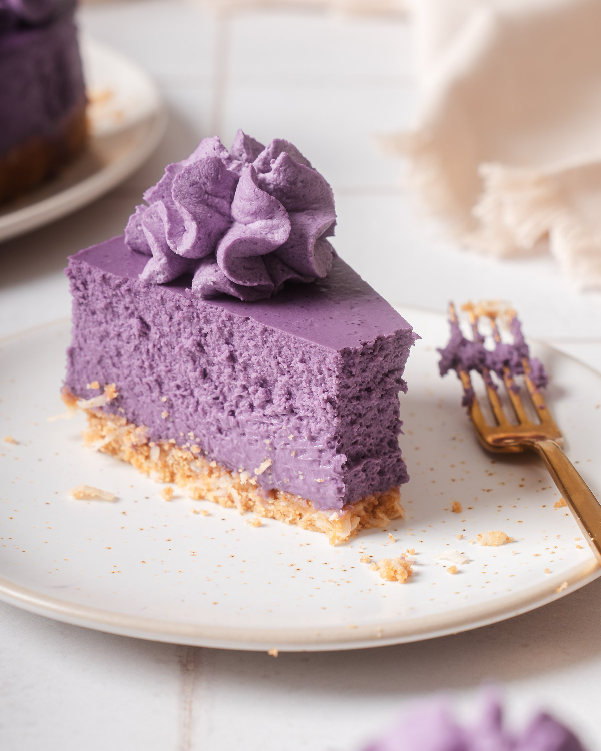 A slice of ube cheesecake with a bite out of it.